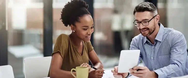 Businessman and businesswoman smile at a tablet showing recruitment industry data