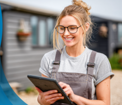 Woman looks at Sage Intacct on her tablet next to her home blurred in the background