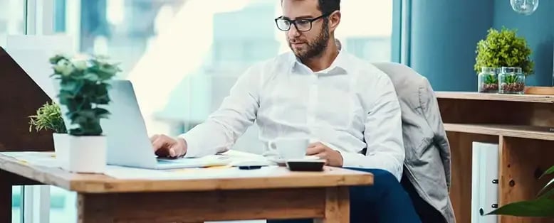 Businessman with glasses uses his laptop to look at data from his SaaS subscription management software