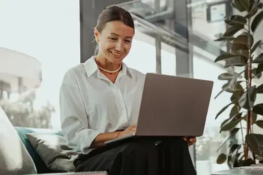 Smiling woman on laptop in office, happy to see Bullhorn integrated with Sage Intacct