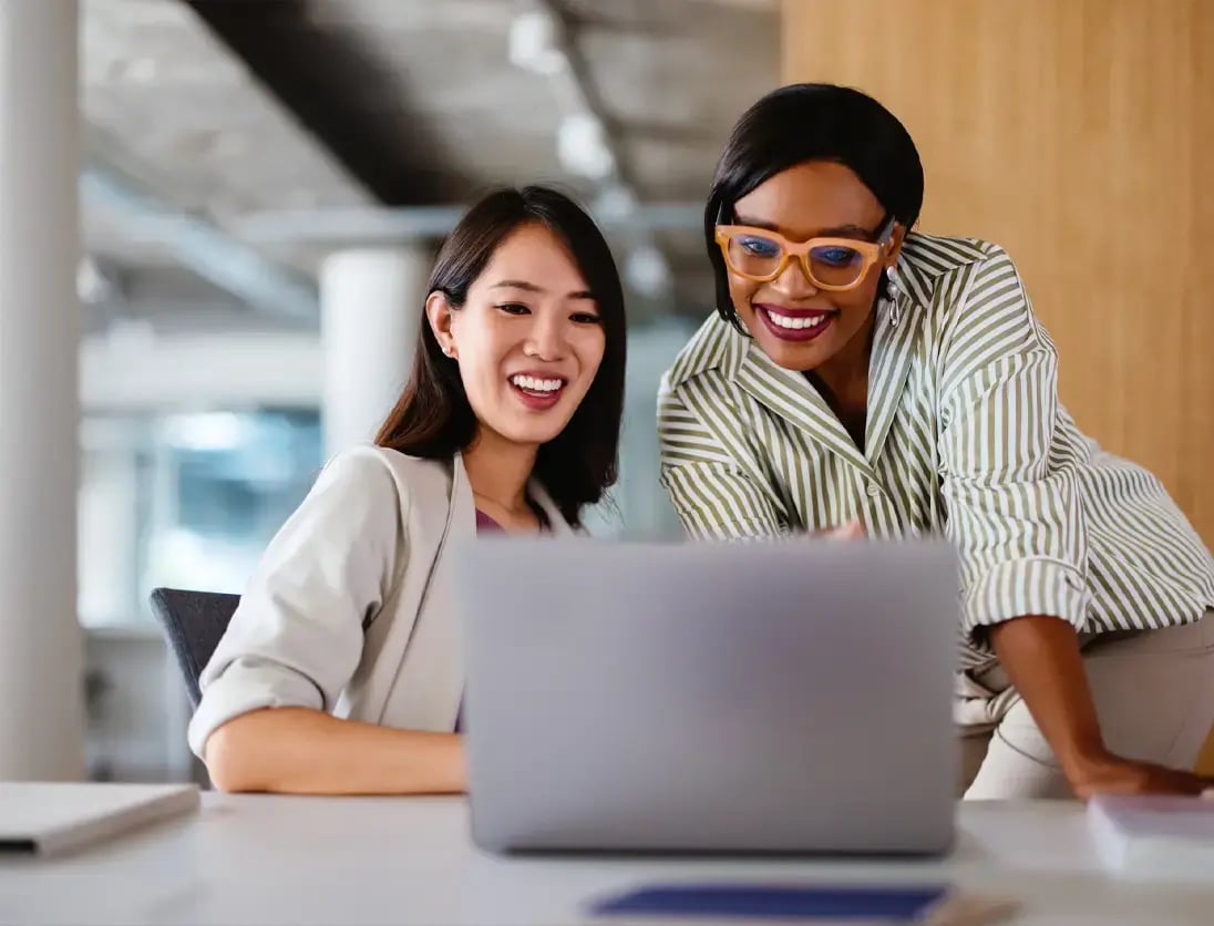 Two workers look closely at a laptop screen to watch how Copilot for SAP Business One works