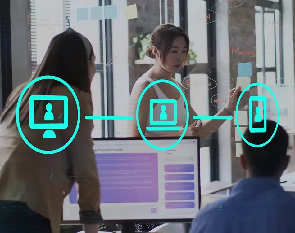 Co-workers in an office with Sage HCM on the computer screen and documents in one workers hands