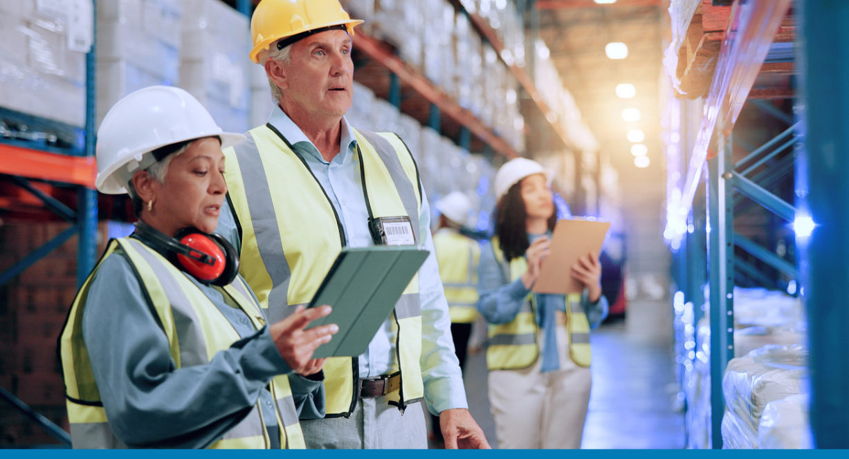 Man and woman in safety gear in a warehouse use an SAP cloud ERP solution on a tablet to track inventory.