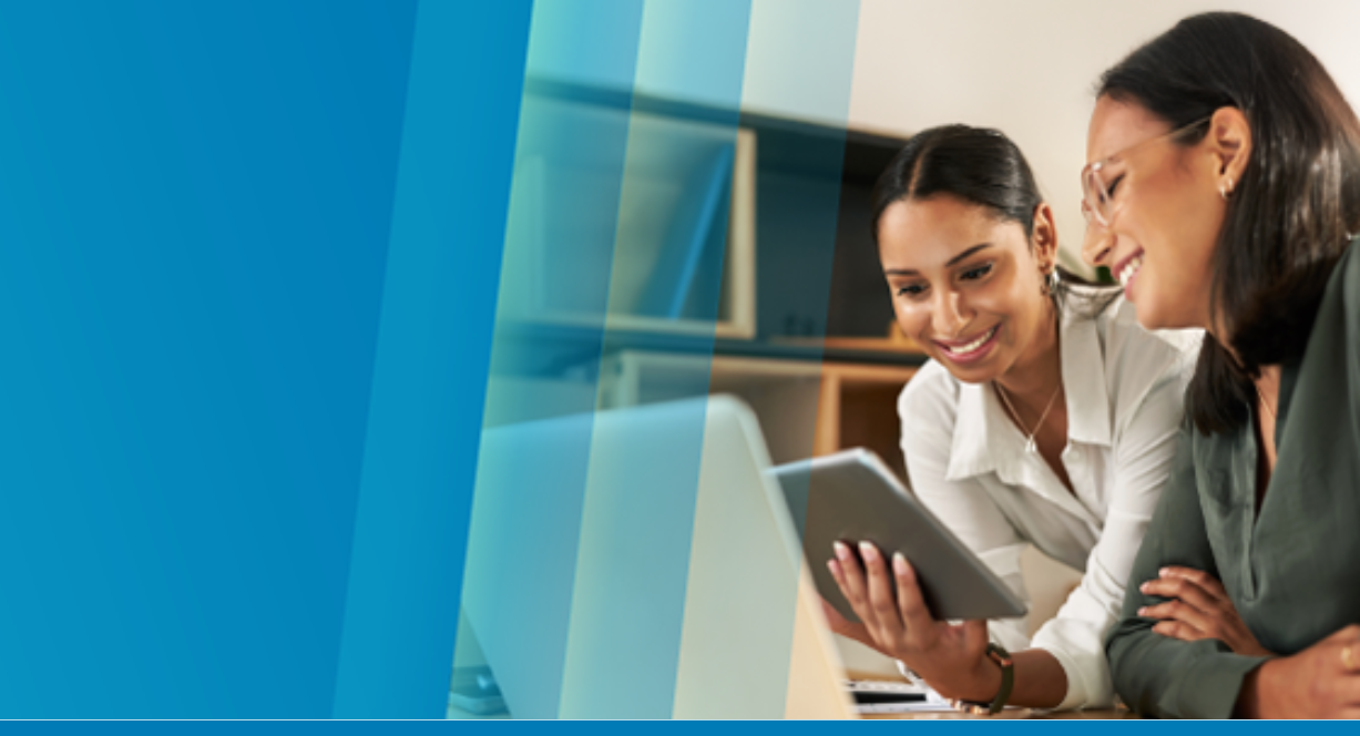 Two smiling businesswomen use Copilot for SAP Business One on a tablet in an office