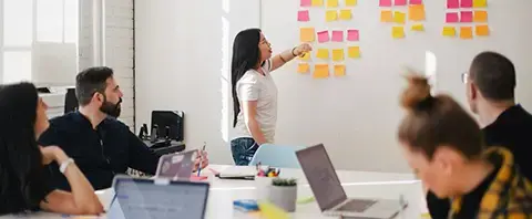 Group of coworkers in an office brainstorm about SAP Business One integration on a Kanban-style whiteboard