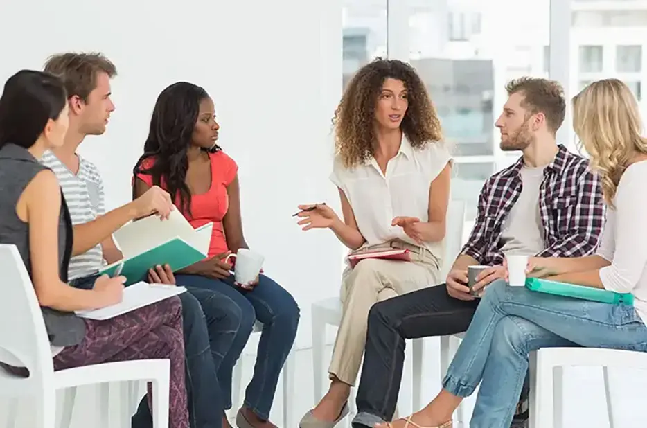 six community living employees sitting on a chair in a spacious office discussing finance